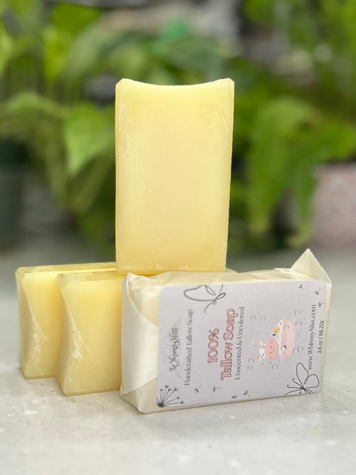 Two yellow soap bars with a packaging box on a light surface with greenery in the background