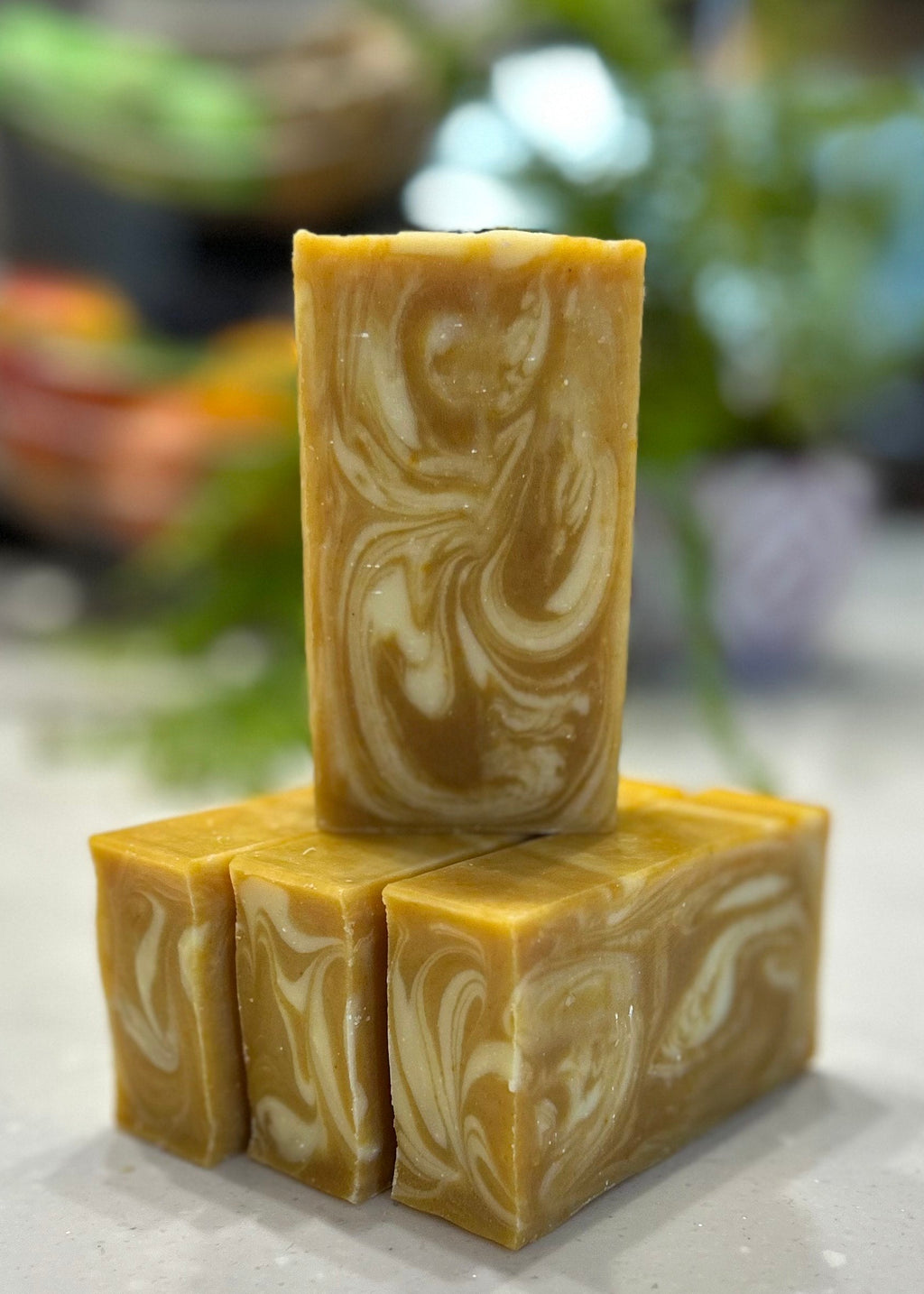Three bars of marbled soap stacked on a marble surface with a blurred background
