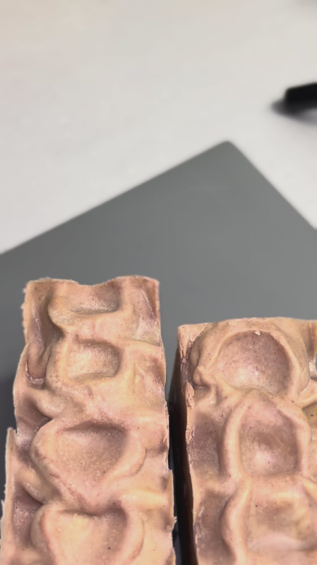 Video of two uncut pink soap loaves on top of a gray sheet.